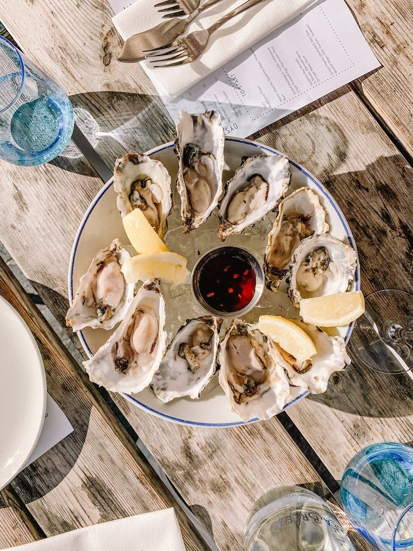 Fresh oyster platter with lemon wedges and mignonette sauce served at a sunlit Cape Town restaurant